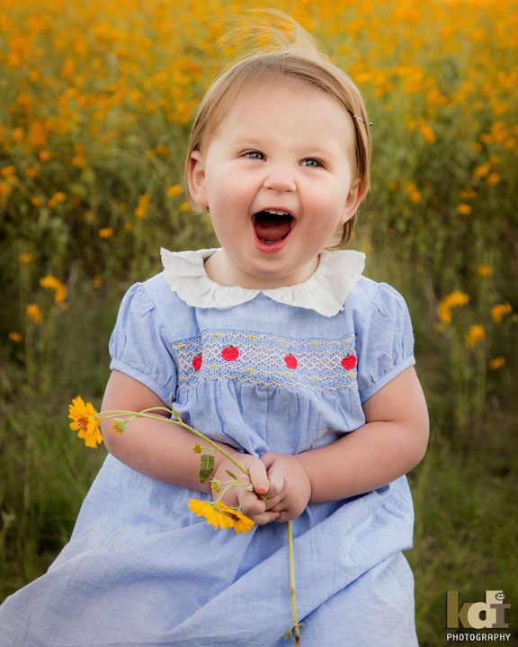 Laughing 12 month old girl in the yellow flowers of summer in Flagstaff,portrait by KDI Photography