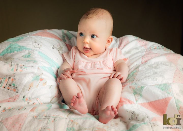 Baby smiles while sitting on blanket. Studio portrait by Flagstaff newborn photographer KDI Photography