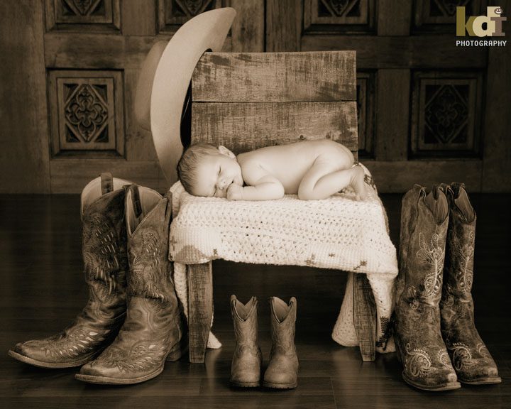 Newborn baby sleeps on a wooden chair with boots and cowboy hat. Flagstaff, AZ