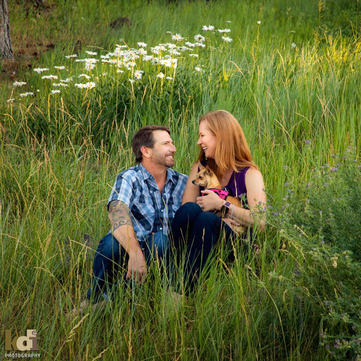 Portrait of Couple Sitting in Flowers in Flagstaff AZ, Holding Their Dog