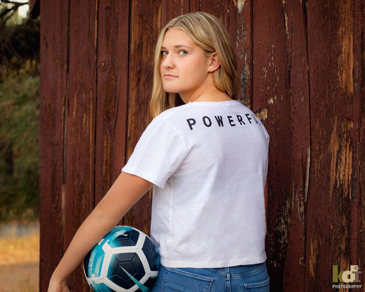 location portrait, senior portrait of girl in front of barn, holding soccer ball in Flagstaff, AZ