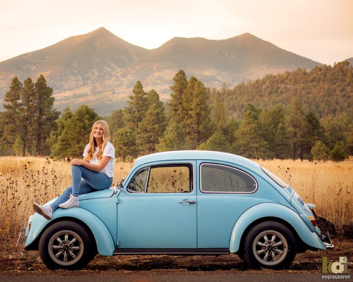 senior photo of girl sitting on classic Volkswagen Beetle with San Francisco Peaks in background,  Flagstaff, AZ