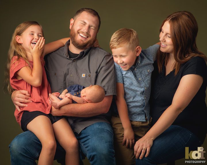 Studio portrait of family of 5 laughing, holding newborn baby, Flagstaff, AZ