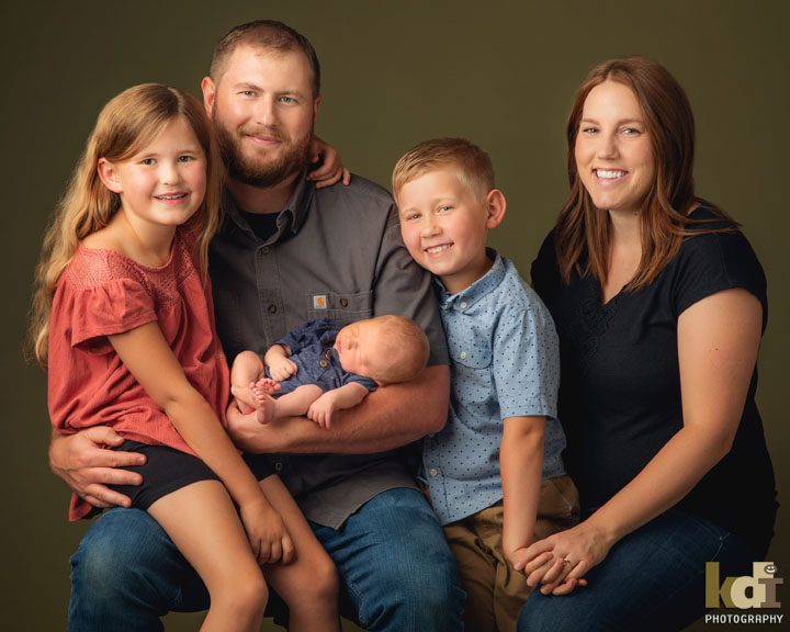 Studio portrait of family of 5 smiling, holding newborn baby, Flagstaff, AZ