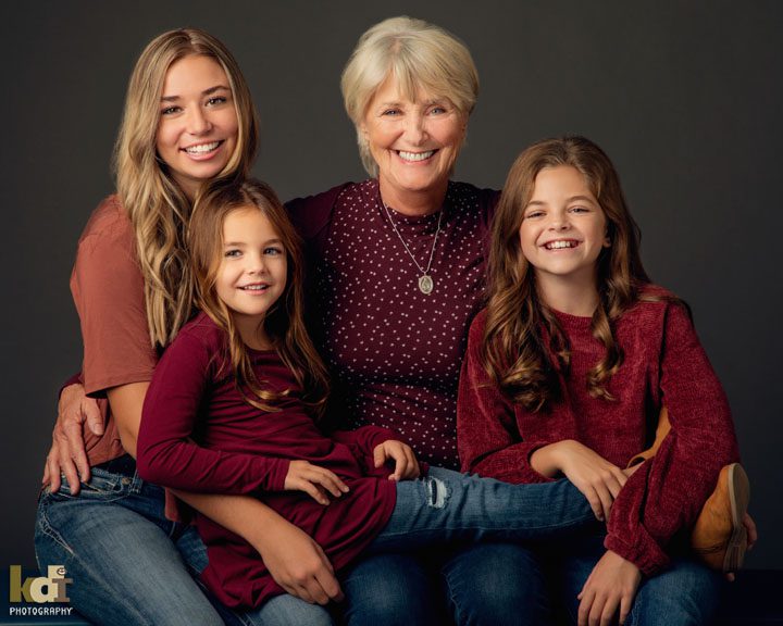 Studio portrait of 3 generations of extended family, grandmother with her 3 granddaughters, snuggling in family photos, Flagstaff