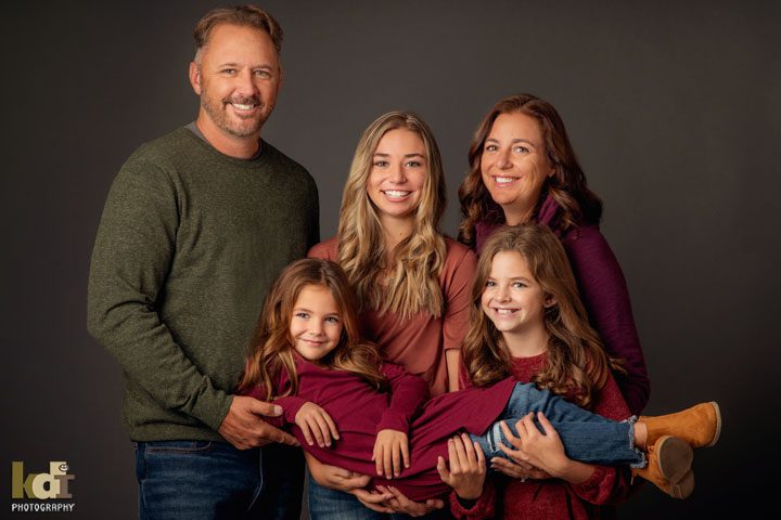Studio portrait of family of 5, carrying youngest, laughing in family photos, Flagstaff