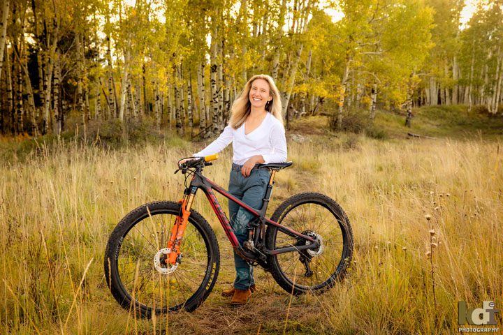 Senior portrait of a mountain biker and her bike with aspens in fall colors, Flagstaff AZ