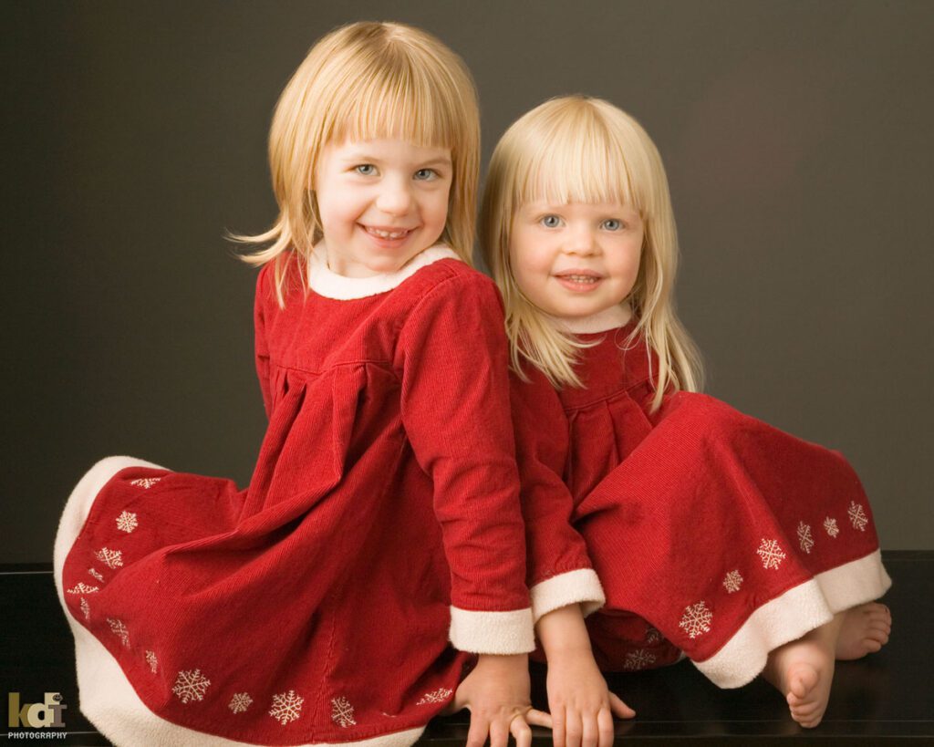 Color studio portrait of sisters in red dresses, by Flagstaff Photographer.