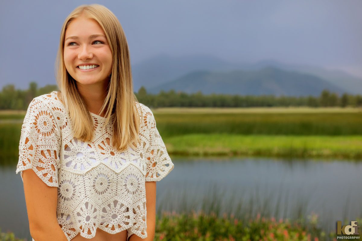 High School Senior Photos of a Gril In White Patterned Top Near a Northern Arizona Lake, with Dogs and Beautiful Flowers, By KDI Photography in Flagstaff, AZ