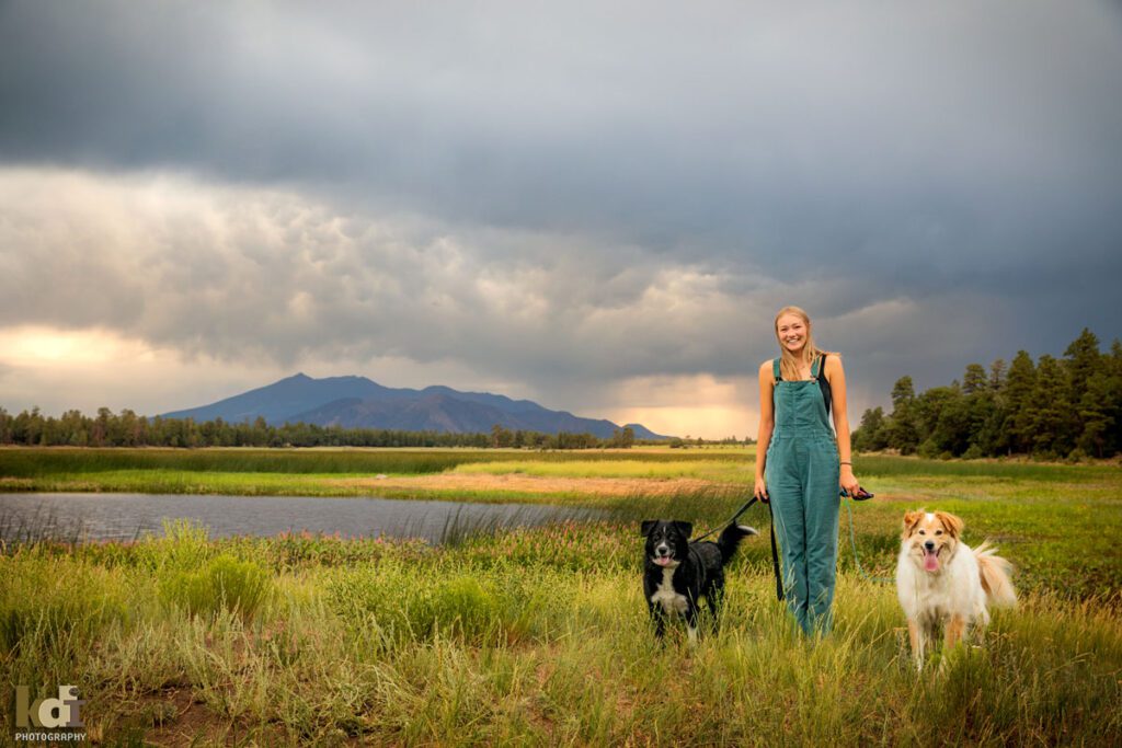 High School Senior Photos of a Girl in Overalls Near a Northern Arizona Lake, with Dogs and Beautiful Flower, By KDI Photography in Flagstaff, AZ