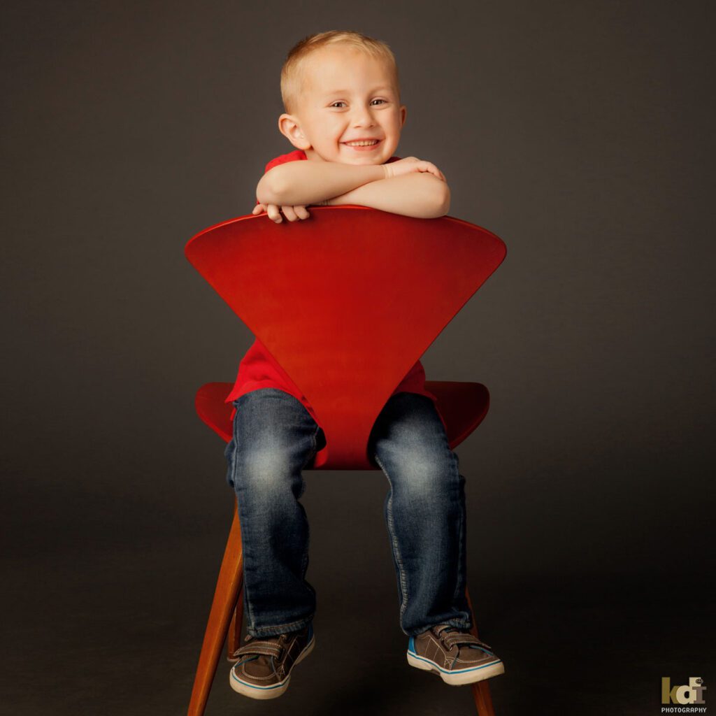 Little Boy Smiling on Red Chair, Family and Kids Portrait Photographer in Flagstaff, AZ by KDI Photography 