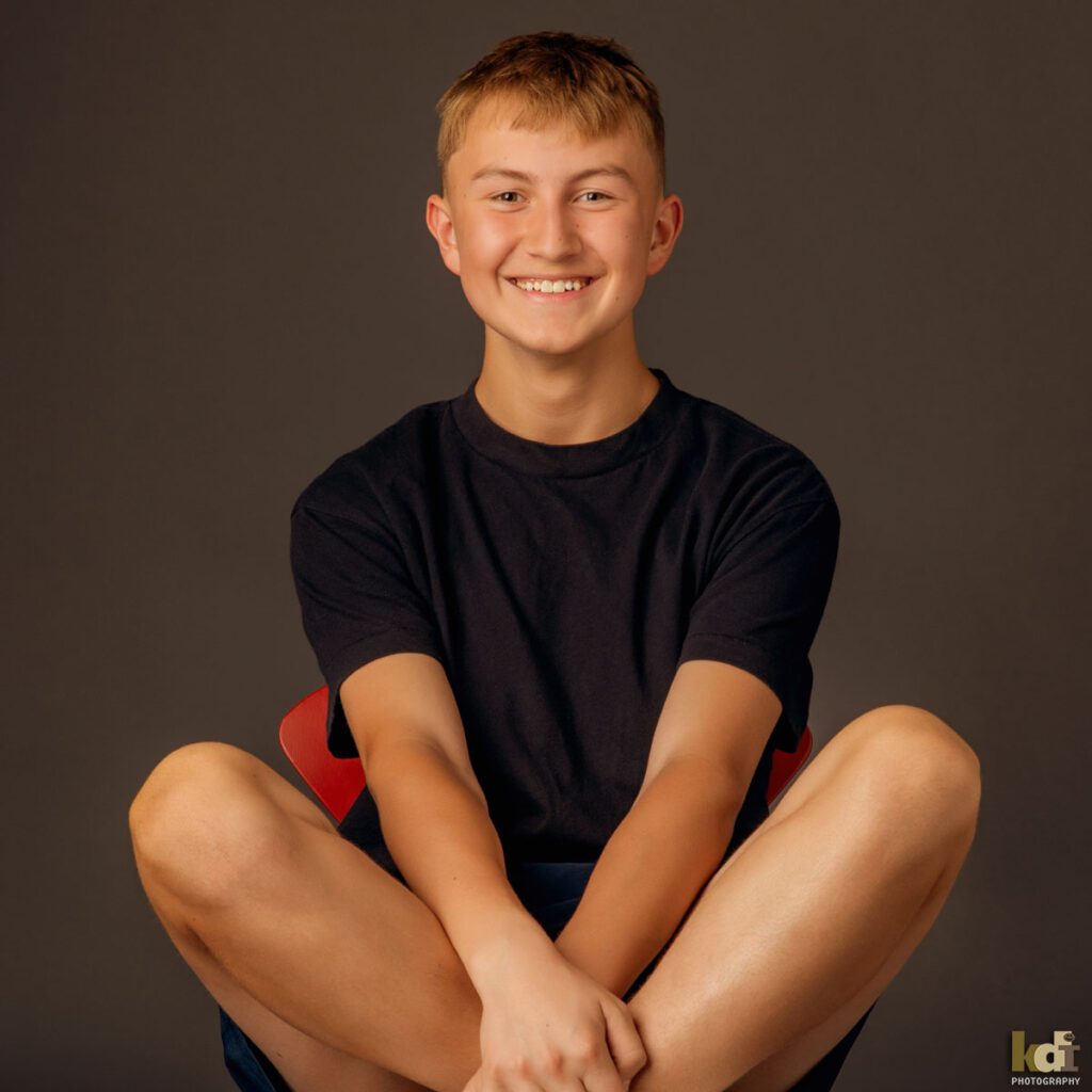 Teen Boy Smiling on Red Chair, Family and Kids Portrait Photographer in Flagstaff, AZ by KDI Photography 