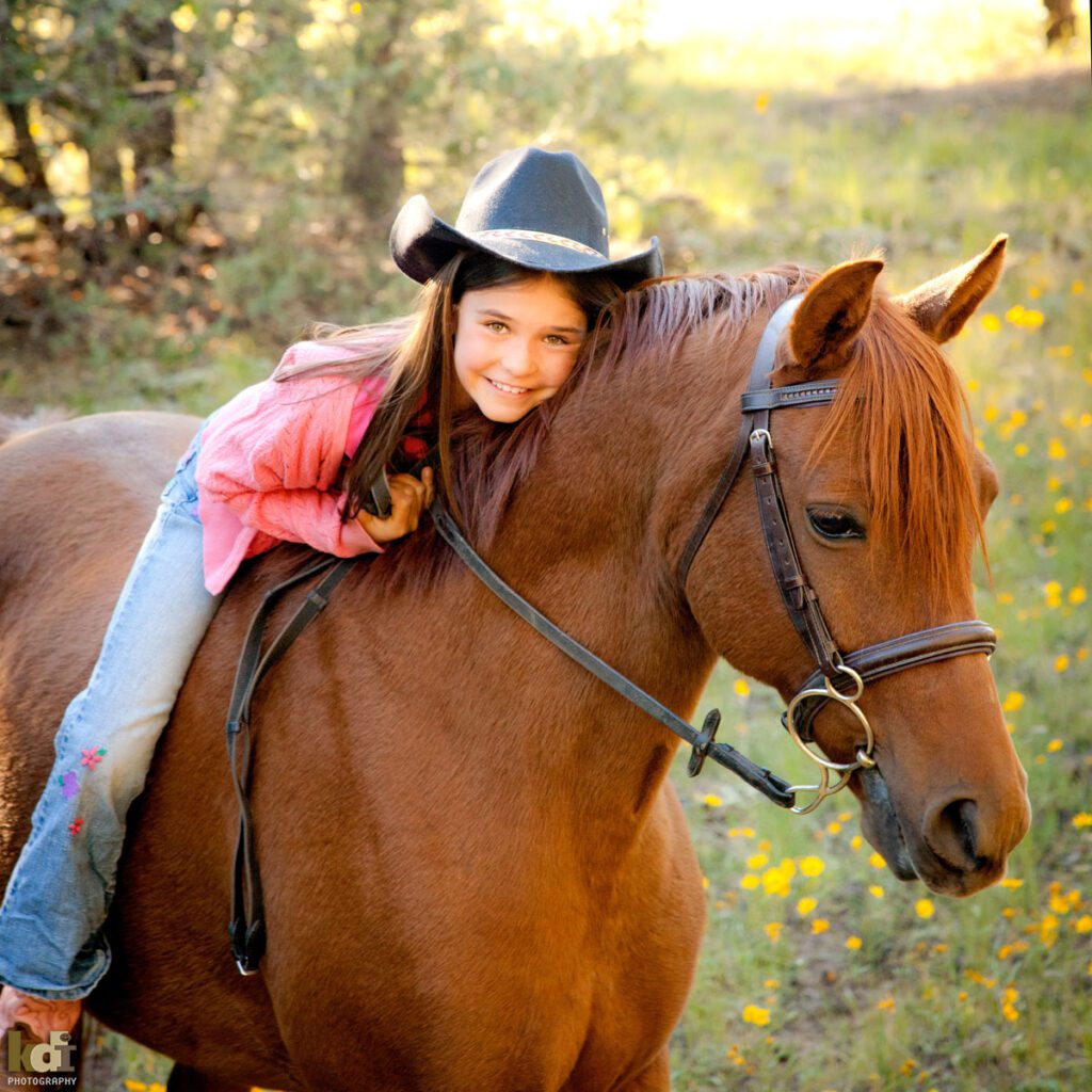 Portrait of a tween preteen girl in cowboy hat, snuggling her horse, location family pictures in Northern Arizona, family photographs by KDI Photography