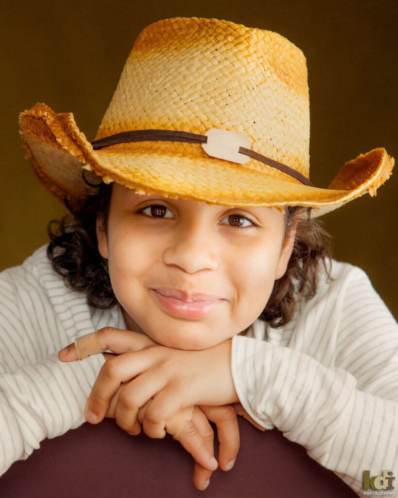 Portrait of a 12 year old boy tween preteen, in cowboy hat with small no teeth smile, studio family pictures in Northern Arizona, family photographs by KDI Photography
