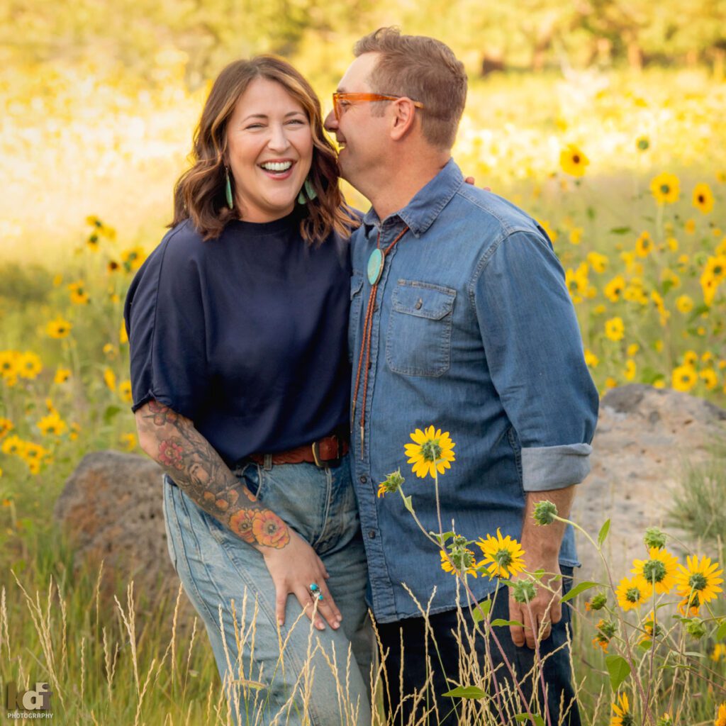 A family photo session in a field of flowers with a husband and wife laughing in Flagstaff Arizona, location portraits by KDI Photography