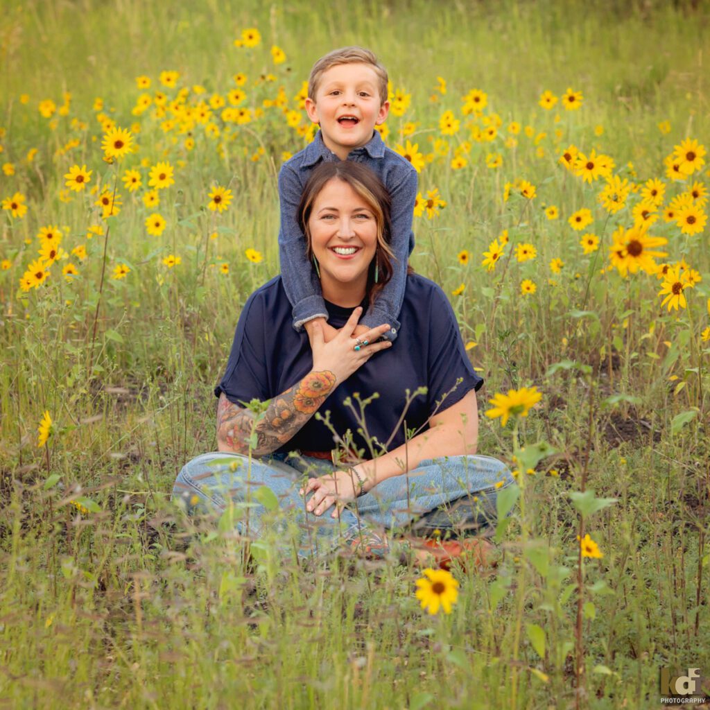 A family photo session in a field of flowers with a mother and son laughing in Flagstaff Arizona, location portraits by KDI Photography