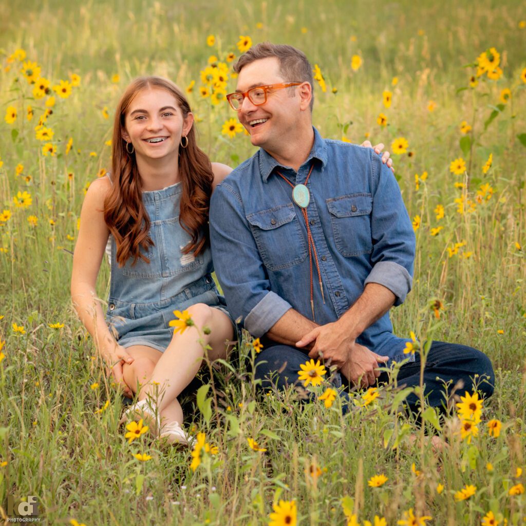 A family photo session in a field of flowers with a father and daughter laughing in Flagstaff Arizona, location portraits by KDI Photography