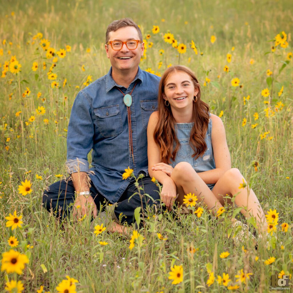 A family photo session in a field of flowers with a father and daughter laughing in Flagstaff Arizona, location portraits by KDI Photography