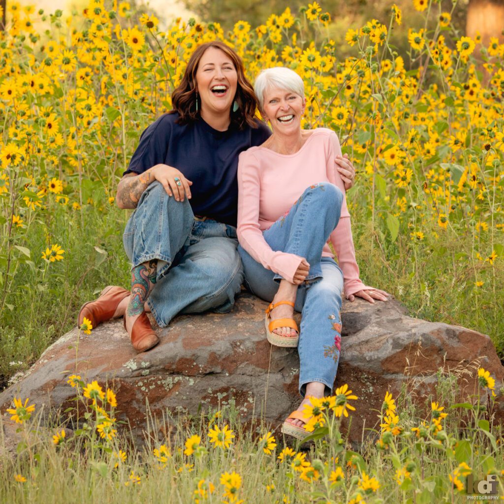 A family photo session in a field of flowers with a grandmother and her adult daughter laughing in Flagstaff Arizona, location portraits by KDI Photography