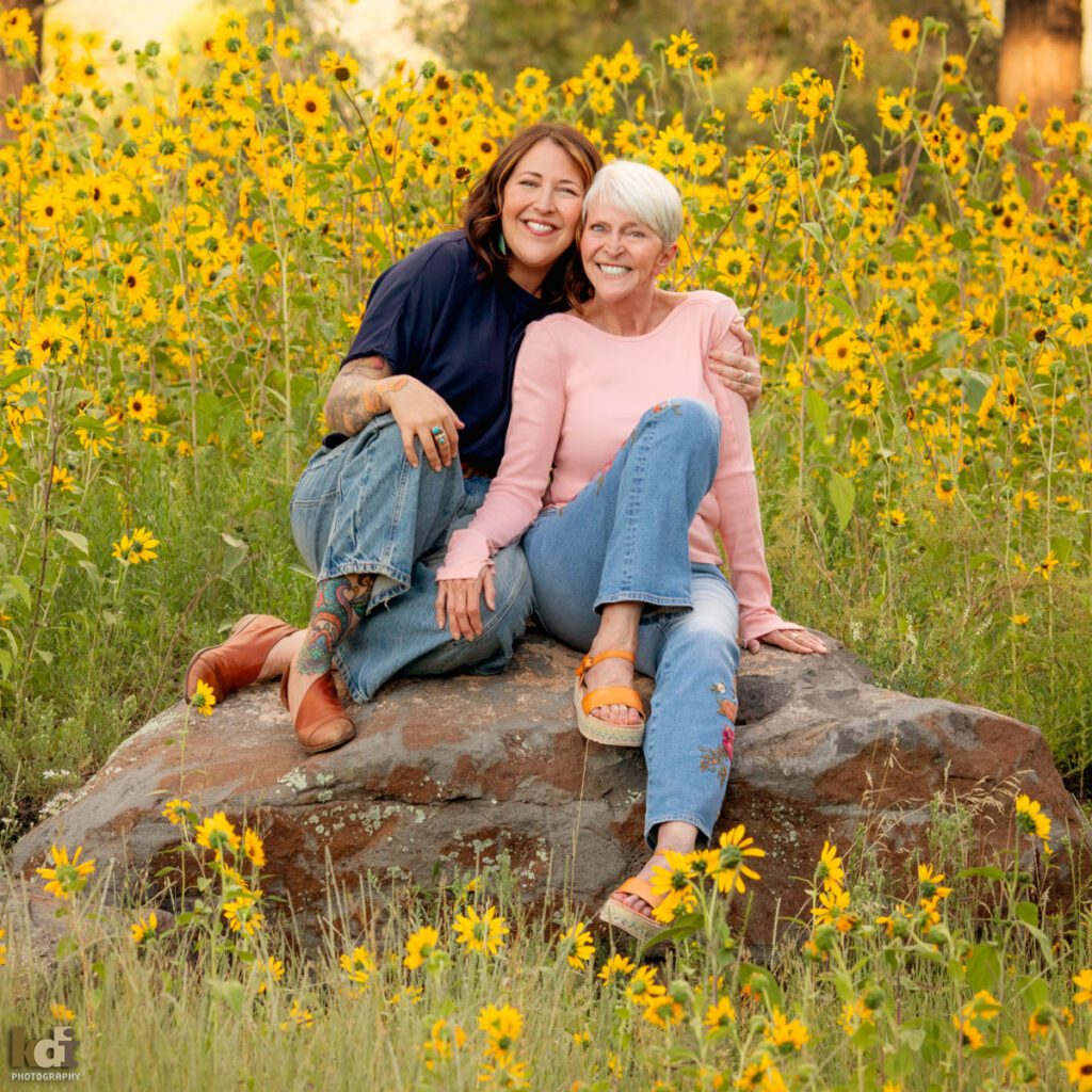 A family photo session in a field of flowers with a grandmother and her adult daughter laughing in Flagstaff Arizona, location portraits by KDI Photography