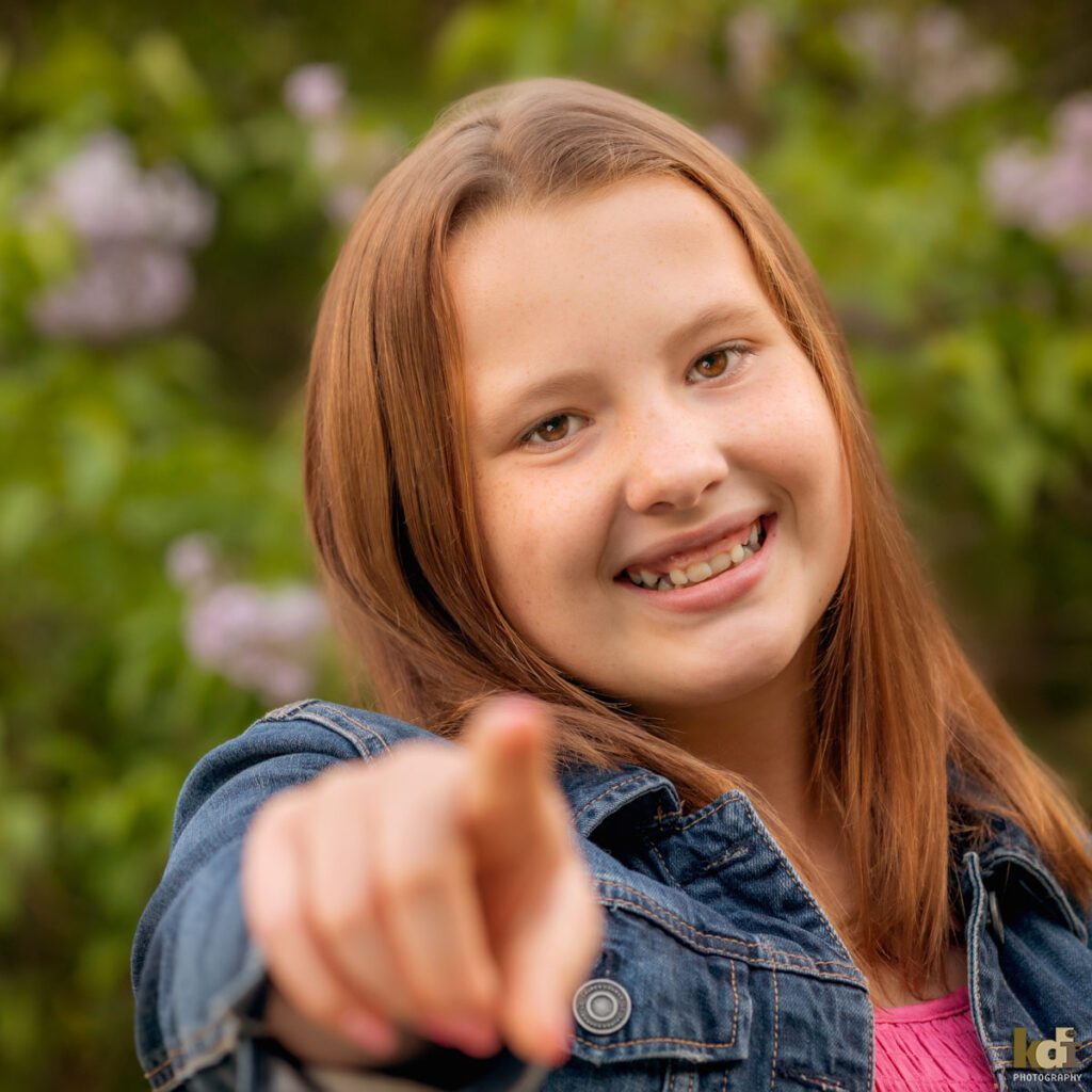 KDI Photography portrait of tween girl in jean jacket, laughing and pointing at camera in Sedona AZ