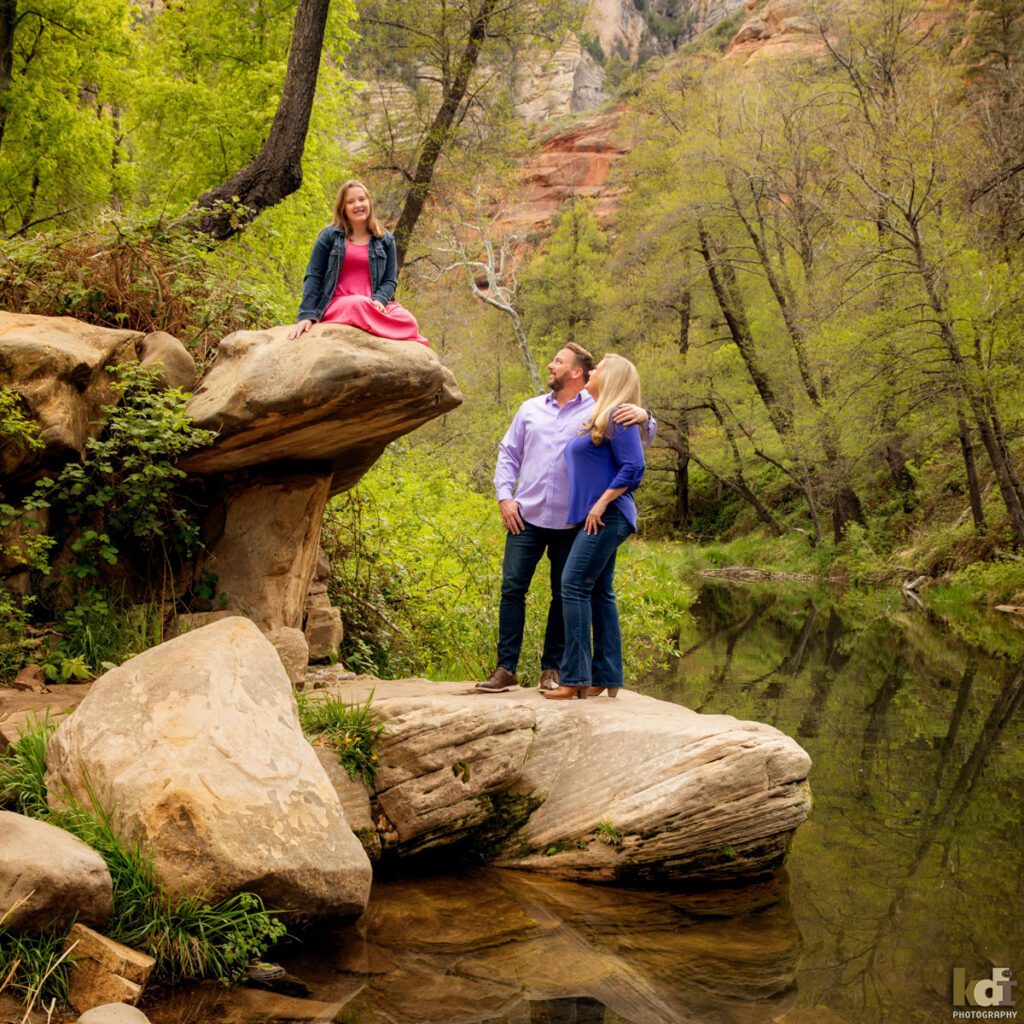 Portrait of father, mother, and preteen tween daughter, sitting on rocks by a creek in Sedona AZ, photographic art by KDI Photography.
