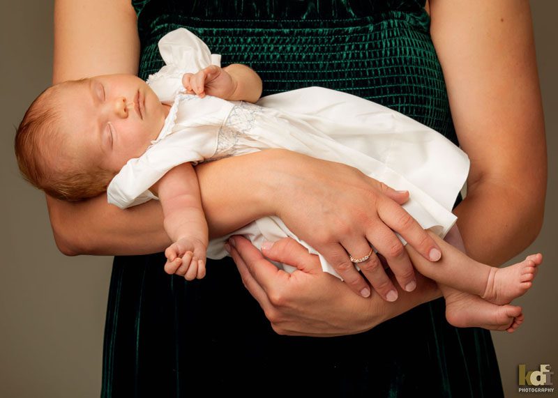 Family photos of a mother's arms holding a newborn girl who is calmly asleep, studio portraits in Northern Arizona, family portraits by KDI Photography