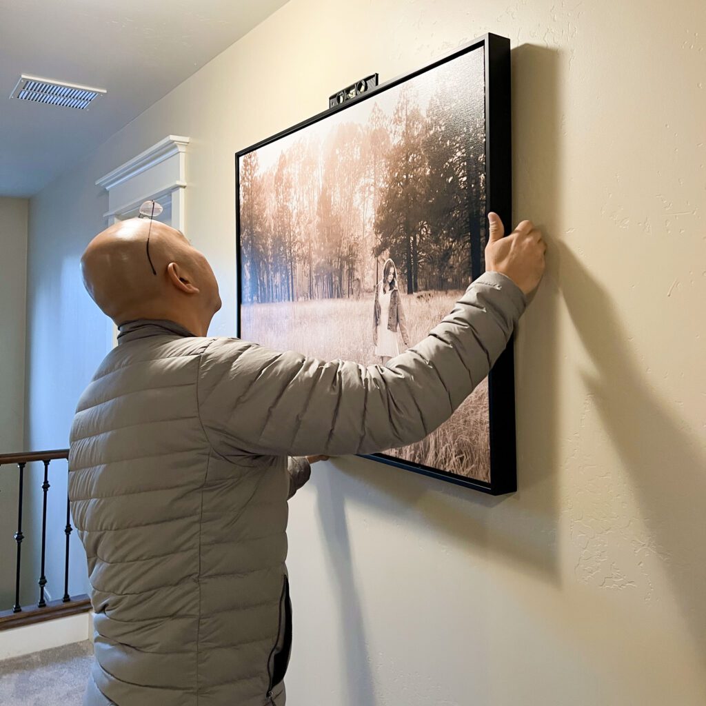 KDI Photography staff install a framed canvas wall art portrait featuring a black and white photograph of a high school senior photo showing girl with blond hair, in white dress and jean jacket among the fall aspen trees, portrait photography in Flagstaff AZ by senior photographer KDI Photography