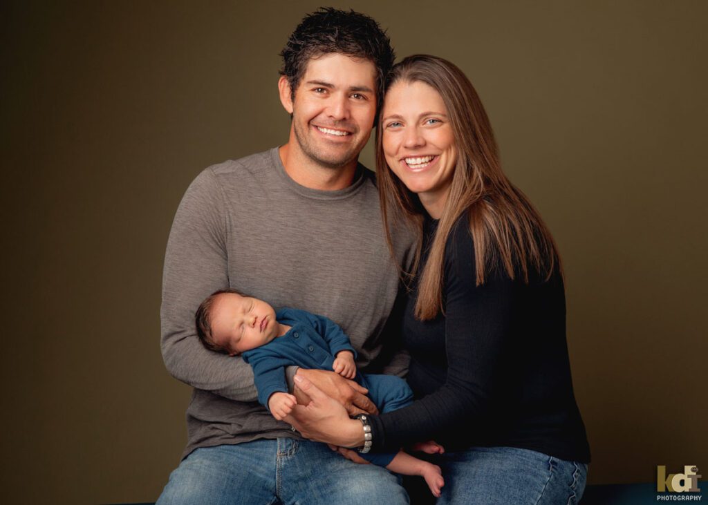 Color newborn photography, portrait of a new baby boy in his parents' arms, in a photo studio in Flagstaff by newborn and family photographer, KDI Photography
