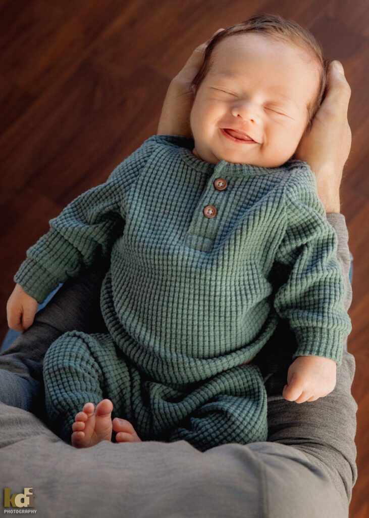 Color newborn photography, portrait of a new baby boy held in his father's arms, in a photo studio in Flagstaff by newborn and family photographer, KDI Photography
