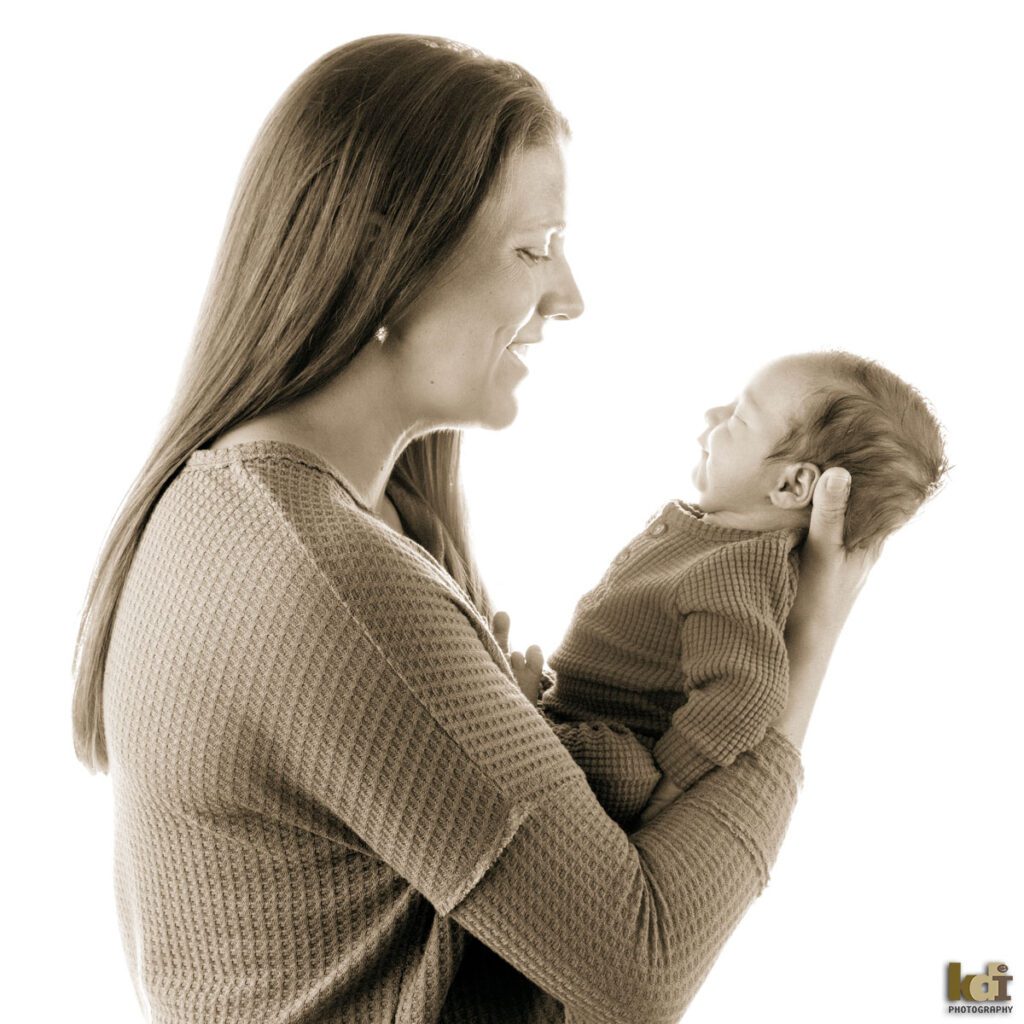 Black and white newborn photography, portrait of a mother and new baby boy held in her arms, in a photo studio in Flagstaff by newborn and family photographer, KDI Photography