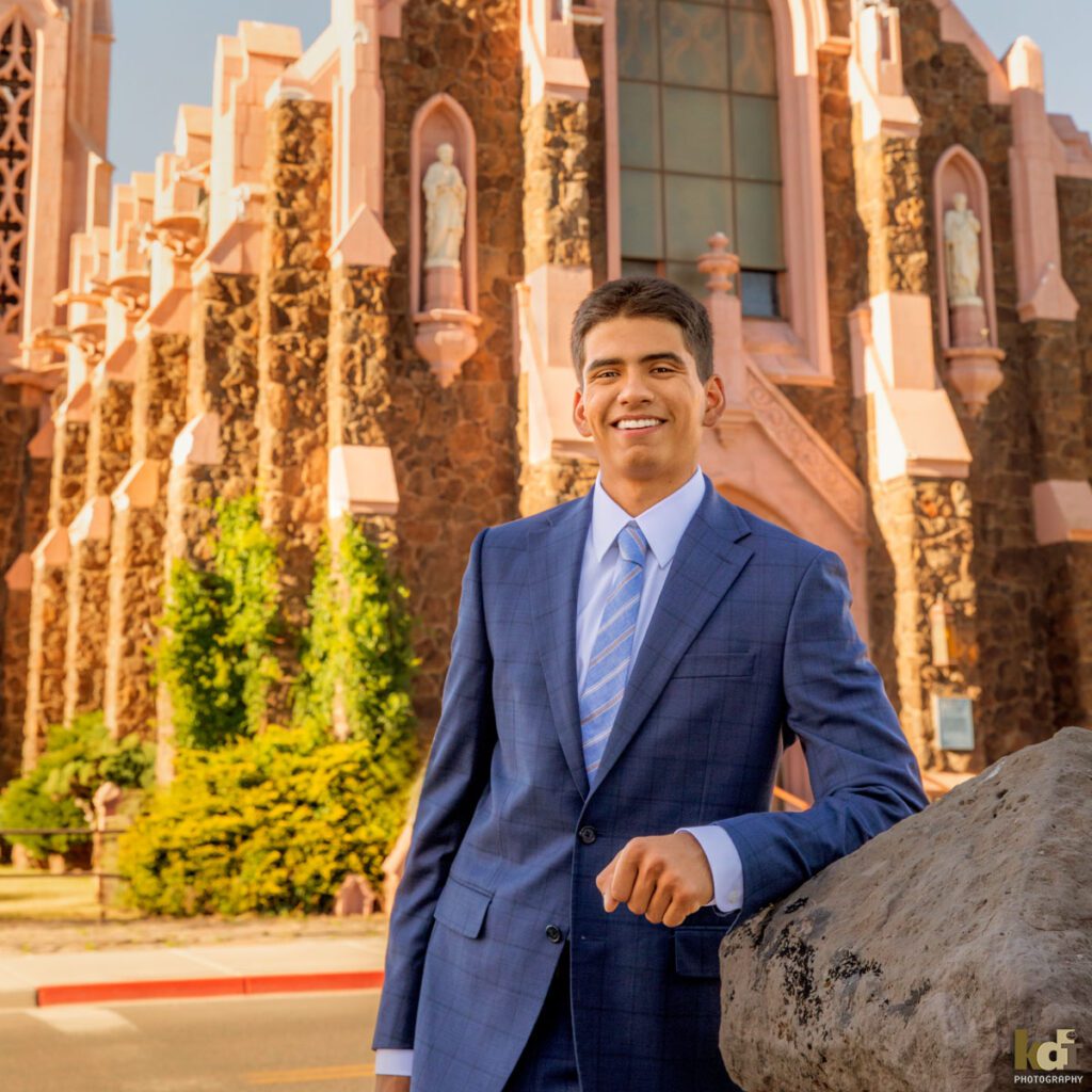 senior photos of a boy shown wearing a suit in front of his church, by Flagstaff family photographer KDI Photography