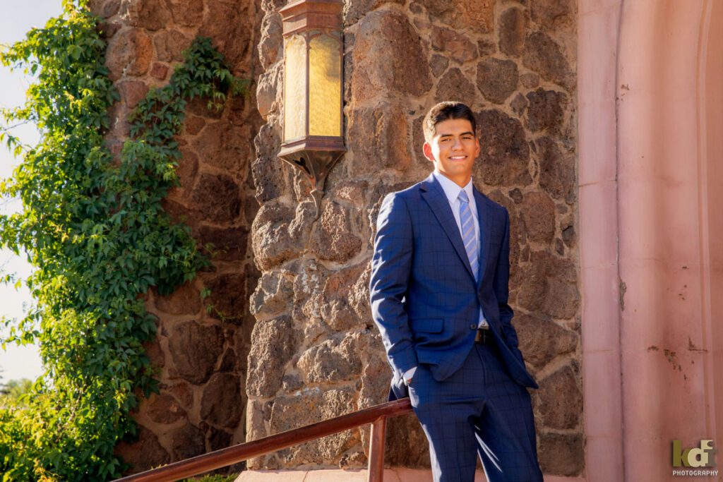 senior photos of a boy shown wearing a suit in front of his church, by Flagstaff family photographer KDI Photography