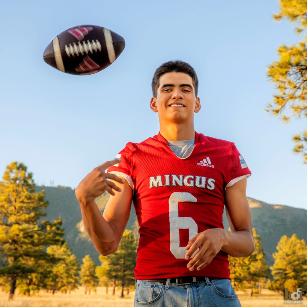 senior photos of a boy shown throwing his football wearing a Mingus High School football jersey with Mount Elden in the background, by Flagstaff family photographer KDI Photography