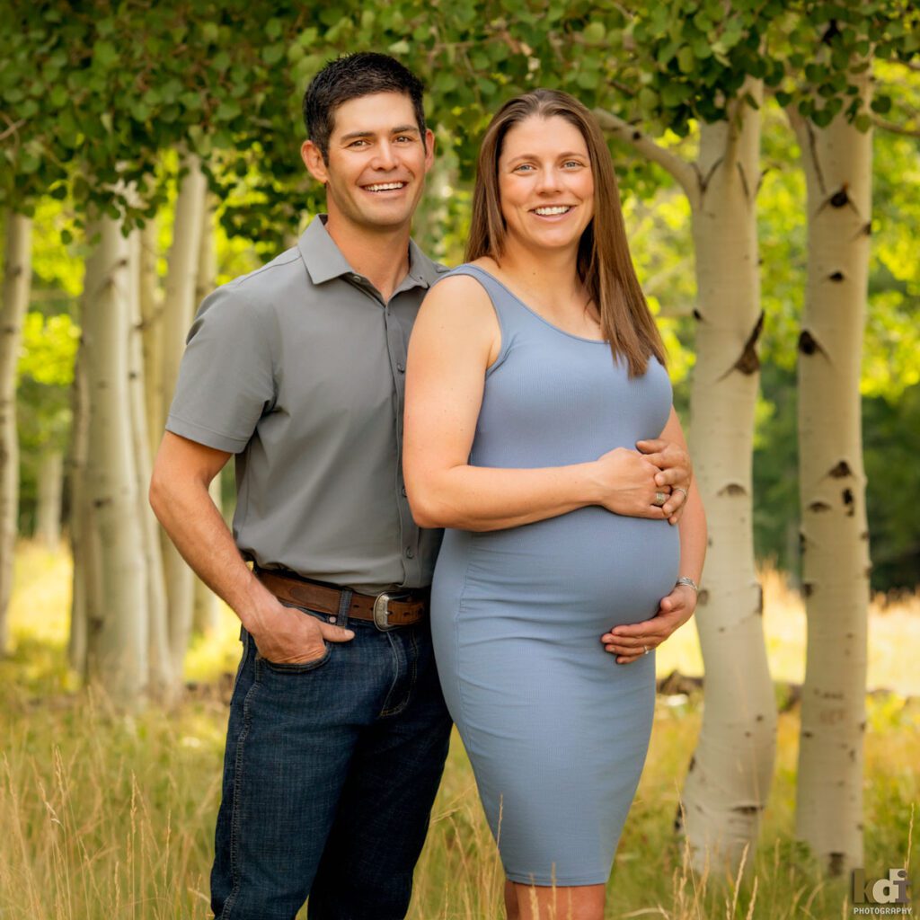 Maternity photography, color portrait of a pregnant couple smiling, on location at the Arizona Snowbowl, in the aspen trees by Flagstaff pregnancy photographer, KDI Photography