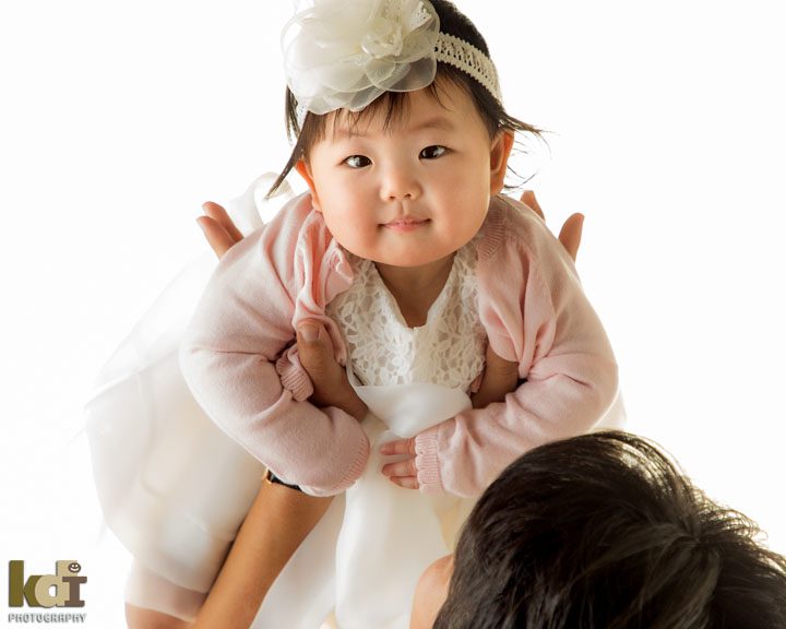 Baby is held up above in her father's hands, baby and family photography by Flagstaff photographers KDI Photography