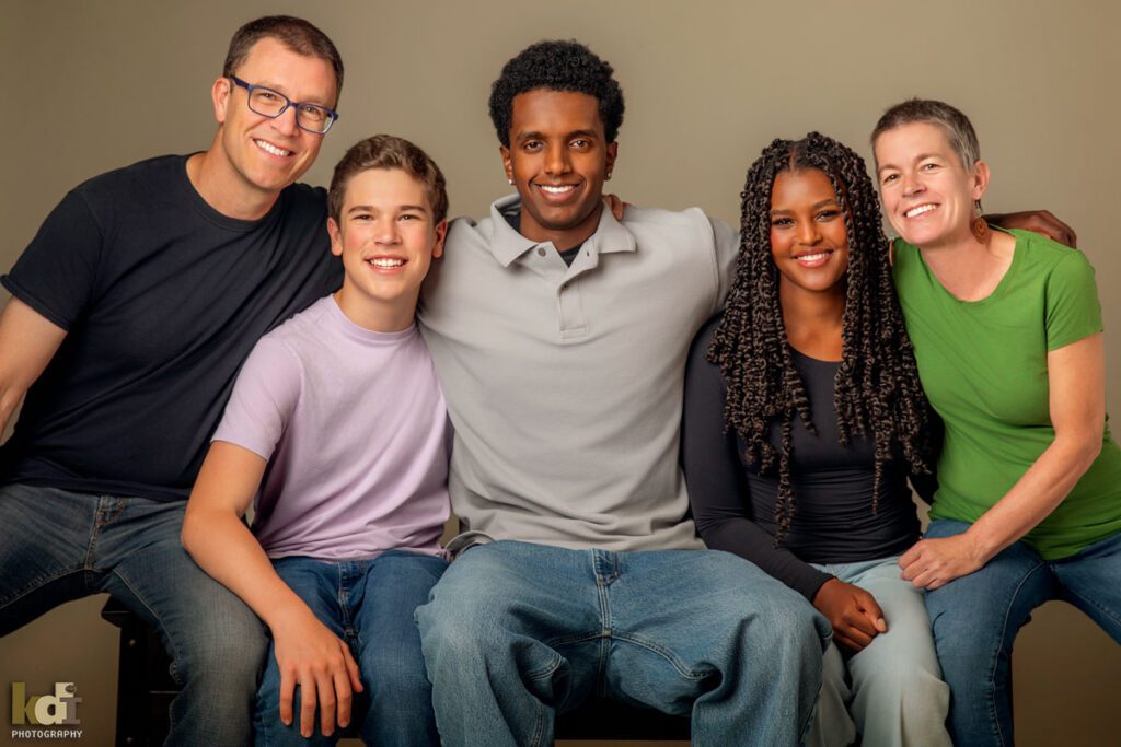 Color photograph of a studio family photo of a woman with recently shaved hair due to cancer treatment, with her husband and three teenage children, family photography by Flagstaff portrait artist KDI Photography