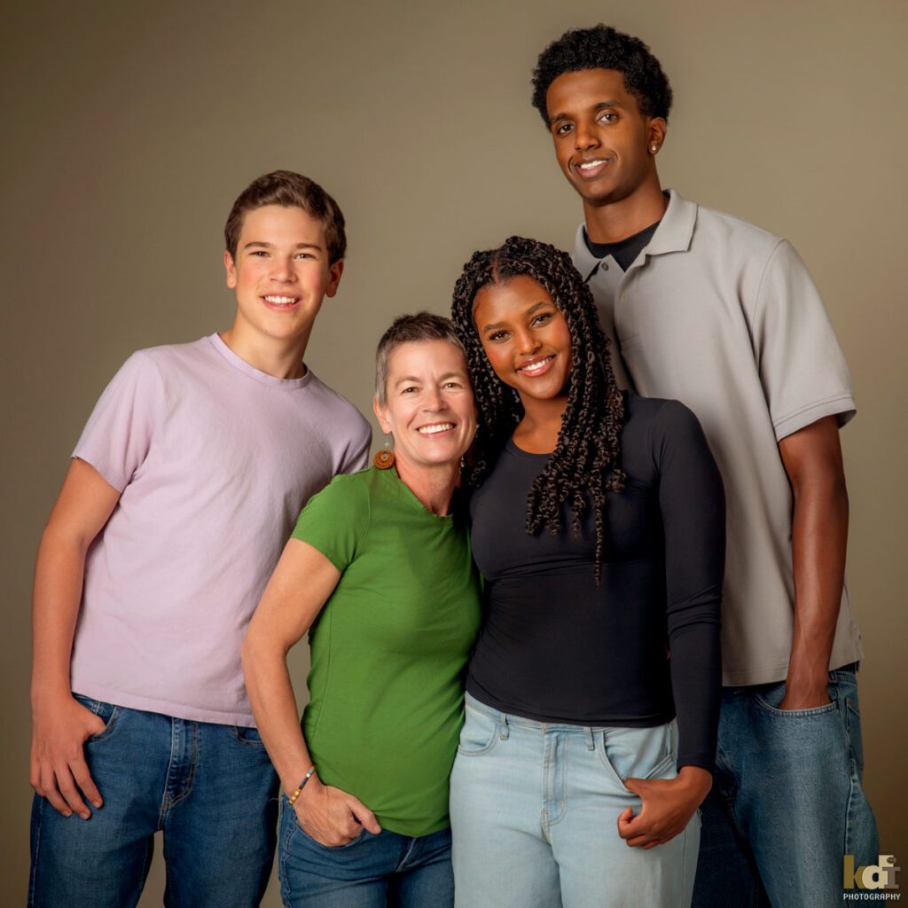 Color photograph of a studio family photo of a mother with recently shaved hair due to cancer treatment, with her teen daughter and two sons, family photography by Flagstaff portrait artist KDI Photography