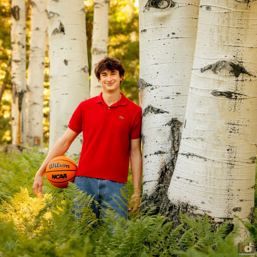 Color senior photo of high school senior boy with red shirt holding basketball, photographic artwork in Flagstaff, by Flagstaff photographer KDI Photography