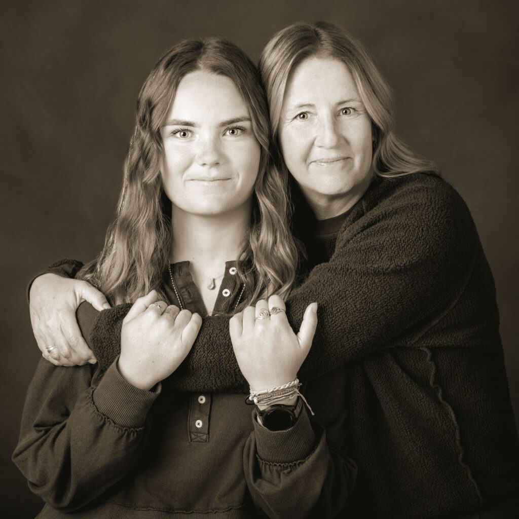 Mother hugs her adult daughter in a black and white studio family photo, portrait art by Flagstaff photographer, KDI Photography