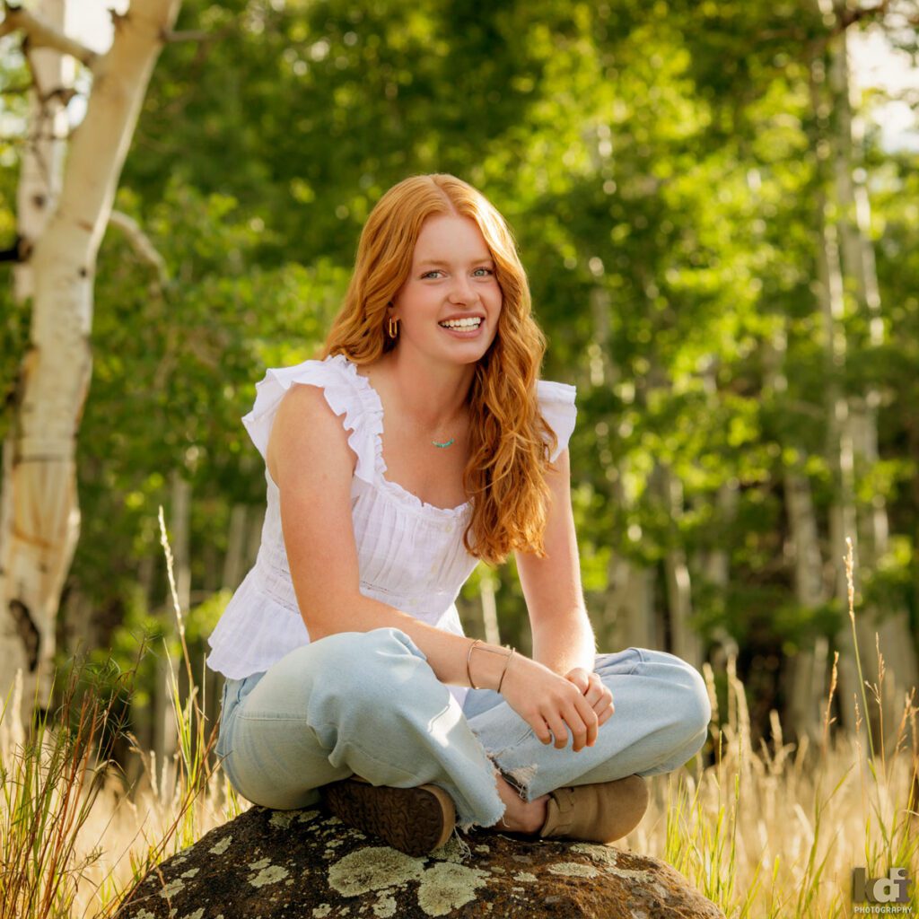 High school senior photos showing girl with red hair, wearing jeans and white shirt, in the San Francisco Peaks of Northern Arizona, portrait photography in Flagstaff AZ by senior photographer KDI Photography