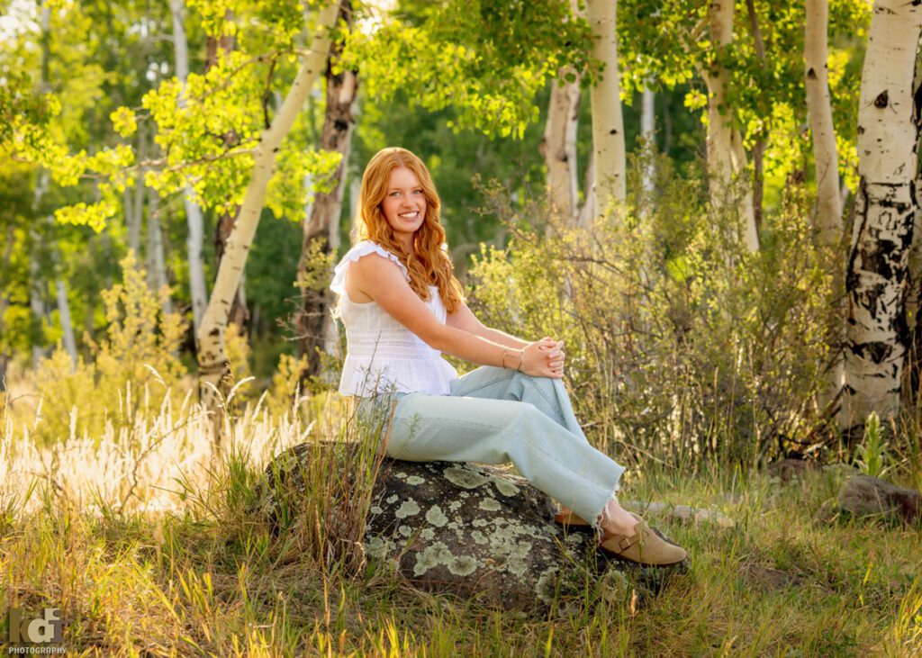 High school senior photos showing girl with red hair, wearing jeans and white shirt, in the San Francisco Peaks of Northern Arizona, portrait photography in Flagstaff AZ by senior photographer KDI Photography