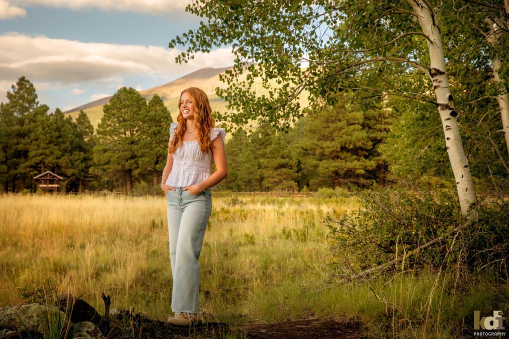 High school senior photos showing girl with red hair, wearing jeans and white shirt, in the San Francisco Peaks of Northern Arizona, portrait photography in Flagstaff AZ by senior photographer KDI Photography