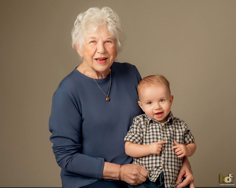 Grandmother and her grandson sit snuggled together laughing in studio family photo, portrait by Flagstaff photographer, KDI Photography