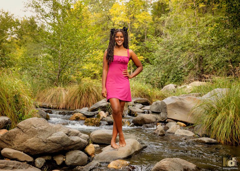 Senior girl in pink dress, stand on rock in Oak Creek, Sedona, AZ senior photo by Flagstaff photographer, KDI Photography